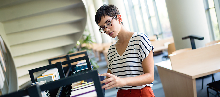 Happy woman at the library taking a book